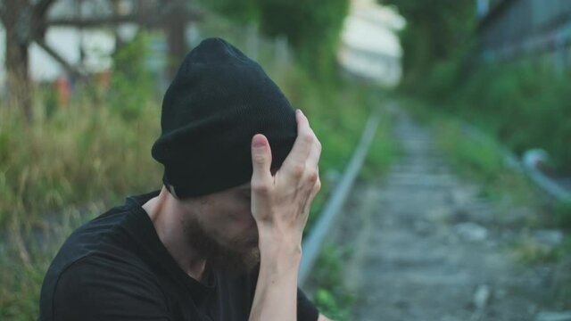 Homeless man with belongings gaunt of hunger ruffles his hat. broken down person, gotten into poverty, misery, been laid off, fired, sacked, burned out. social problems, unemployment concept.