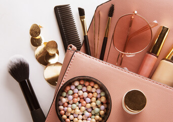 Flat lay of pink leather woman bag open out with cosmetics and accessories