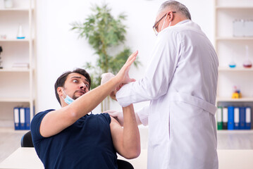 Obraz premium Young male patient visiting old male doctor in vaccination conce