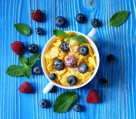 Cornflakes with berries raspberries and blueberries on blue wooden background. Healthy eating, food and diet concept.