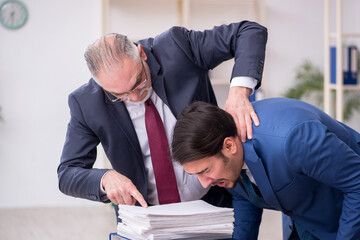 Old boss and young male employee in bullying concept