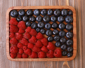 blueberries and raspberries on wooden plate