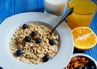 Healthy breakfast, food and diet concept - oatmeal with fresh berries on white plate with orange juice and milk