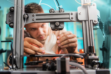 student in the workshop examines the detail printed on a 3D printer.