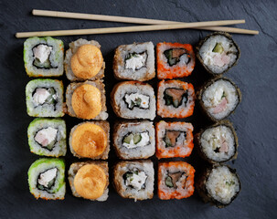 Large sushi set on black. An assortment of various maki, nigiri and rolls. Close up. Top view.