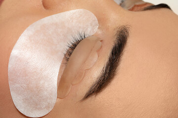 Young woman undergoing eyelash lamination, closeup. Professional service
