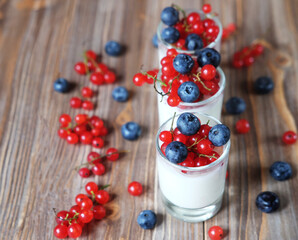 yogurt with fresh berries in glass jar, on wooden background