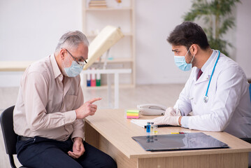 Fototapeta premium Old male patient visiting young male doctor in vaccination conce