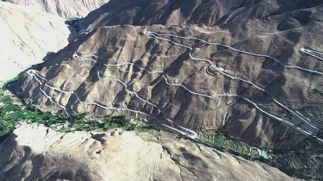 Breathtaking view of a winding mountain road leading across the Tibetan Plateau. Empty asphalt road leads along the steep mountains in the Himalayas. (aerial view)