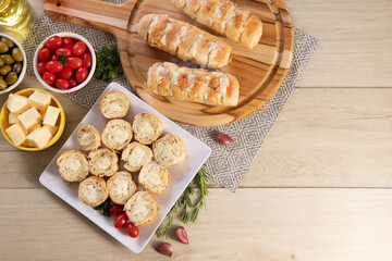 Garlic bread in white square plate on the table with cheese, rosemary, olives and cherry tomatoes. Top view.