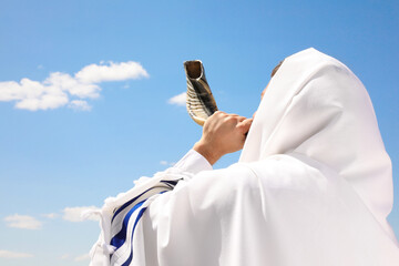 Jewish man in tallit blowing shofar outdoors. Rosh Hashanah celebration - obrazy, fototapety, plakaty