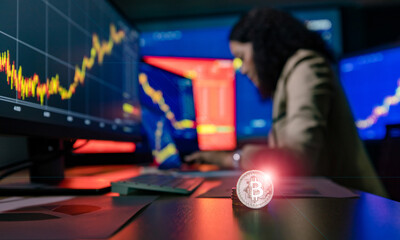 Close up shot of bitcoin cryptocurrency with flare in front female Asian broker trader investor type on laptop computer study graph chart report when make transaction online in blurred background