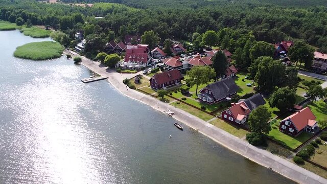Colorful buildings of Pervalka with sun reflection in Curonian Lagoon, aerial view