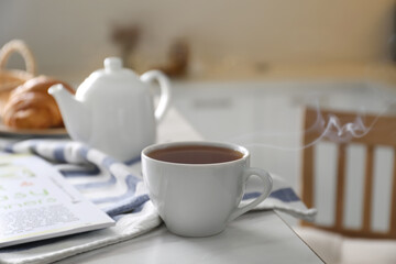 Cup of hot tea served for breakfast on table in kitchen