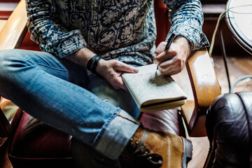 Closeup of journalist man sitting writing notebook - obrazy, fototapety, plakaty