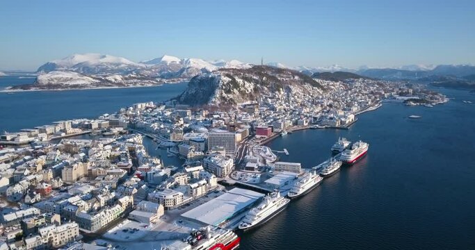 Norway's most beautiful town, Alesund is shown in this breathtaking, winter time, aerial footage that reveals art nouveau buildings, amazing nature, fjords and mountains around it while ascending.