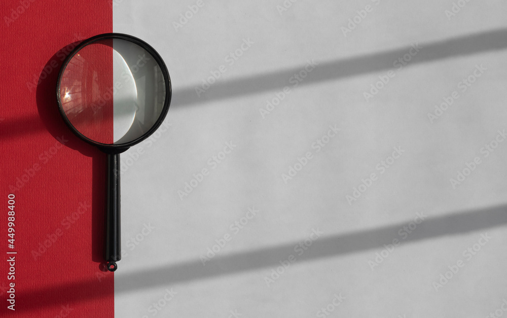 Poster black magnifying glass over white background with red strap and shadow stripes from daylight. search