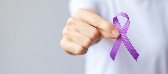 Hand holding purple Ribbon for Pancreatic, Esophageal, Testicular cancer, world Alzheimer, epilepsy, lupus, Sarcoidosis, Fibromyalgia and domestic violence Awareness month. World cancer day concept