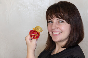 Portrait of a young woman with a handmade brooch on a light background. Facial expression, selective focus, beautiful people. 