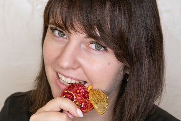 Portrait of a young woman with a handmade brooch on a light background. Facial expression,...