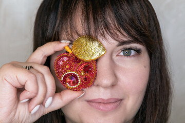 Portrait of a young woman with a handmade brooch on a light background. Facial expression, selective focus, beautiful people. 