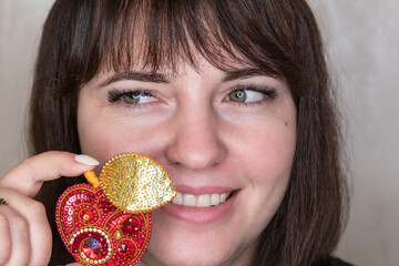 Portrait of a young woman with a handmade brooch on a light background. Facial expression, selective focus, beautiful people. 