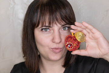Portrait of a young woman with a handmade brooch on a light background. Facial expression, selective focus, beautiful people. 