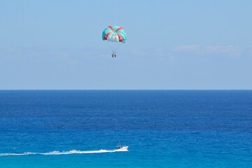 Boat pulls parasailing couple with blue skies and a bluer ocean in background.