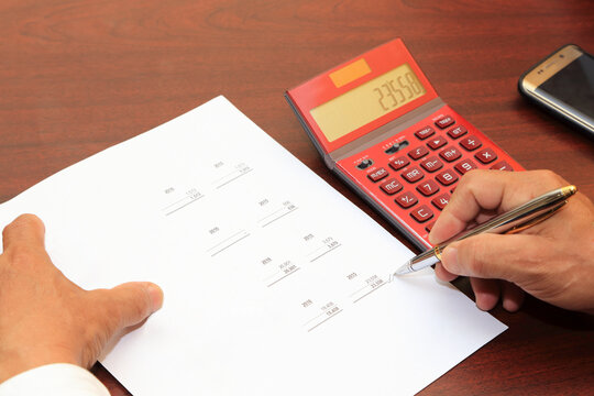 Hombre de negocios realizando suma con hoja de calculo en la mano. Manos de Hombre realizando una suma con calculadora. Operaci&oacute;n Matem&aacute;tica.