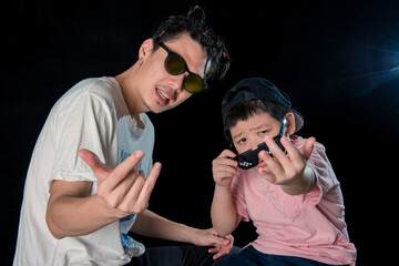 Man and little boy with sunglasses sit looking camera  on dark studio background , asian family