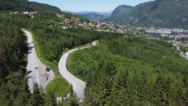 Road E-39 from F&oslash;rde city leading up to mountain through lush evergreen forest - Norway aerial with parallax behind treetops