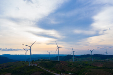 Fototapeta na wymiar Aerial view, windmills rotating by the force of the wind and generating clean renewable energy for sustainable development in a green ecologic way on cloudy sky at highland. Drone shot