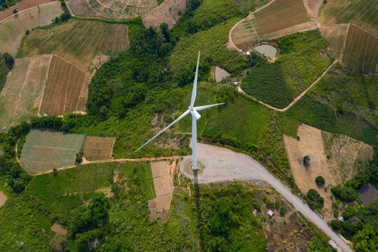 Aerial top view of windmills rotating by the force of the wind for generating clean renewable energy for sustainable development in a green ecologic way at highland. Bird’s eye view shot by drone.