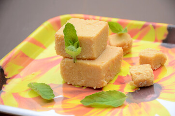 closeup the brown color condensed milk sweet with green mint over out of focus yellow brown background.