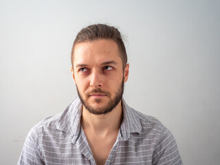 Obraz premium Young Caucasian Male in Grey Shirt Stares Angrily against White Background