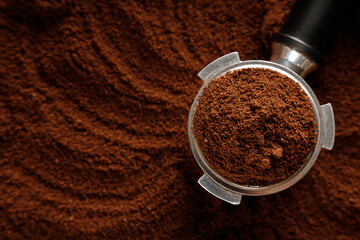 Black ground coffee in coffee holder on coffee background with texture