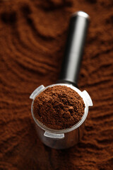 Black ground coffee in coffee holder on coffee background with texture