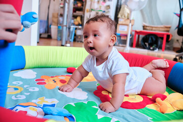 Baby enjoying while playing on a colorful play mat at home.