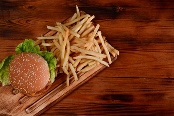 Above view tasty fish burger.and fried potatoes on wooden table.