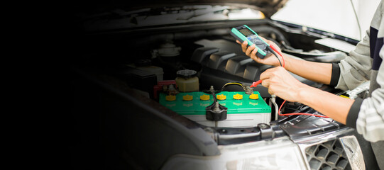A technician is checking the car battery for availability.