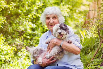 Happy Smiling Senior Woman Hugging her White Havanese Dog Outdoor in the Summer Nature. Active Seniors Concept 