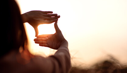 New year planning and vision concept, Close up of woman hands making frame gesture with sunset, Female capturing the sunrise. copy space. - obrazy, fototapety, plakaty