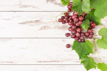 Bunch of ripe green grape with leaves on white wooden background top view.