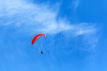 Paramotor flying in a blue sky. Adventure man active extreme sport pilot flying in sky with paramotor engine glider parachute