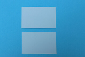 Two light blue blank paper cards on colorful blue background