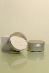 Aluminum cosmetic jar on green background