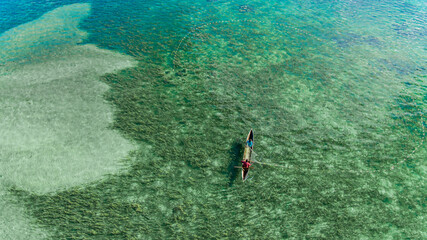 Aerial view of villagers netting fish near the shore.