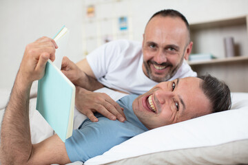 Fototapeta premium happy gay couple lying on bed at home