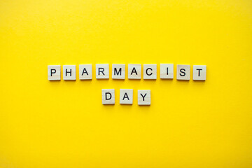 The inscription pharmacist day from wooden blocks on a bright yellow background. High quality photo