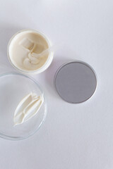 Moisturizing cosmetic cream stands on neutral background with milk splash